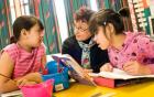 A teacher and two students reading and discussion a book