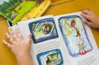 A close up of a workbook with handwriting and illustrations in a child's hands