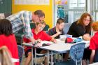 Image of a teacher and teacher's aide working with a group of intermediate-aged students in a classroom